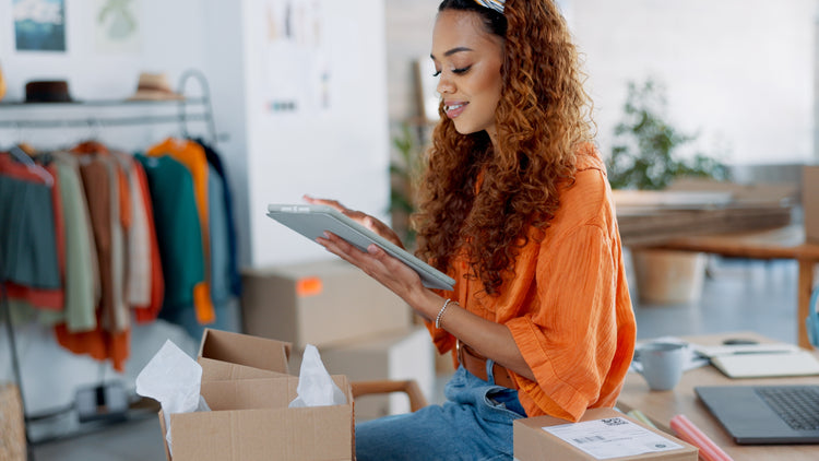 Smiling woman using a tablet in a modern retail space with colorful clothes in the background, alongside a call-to-action message for career inquiries