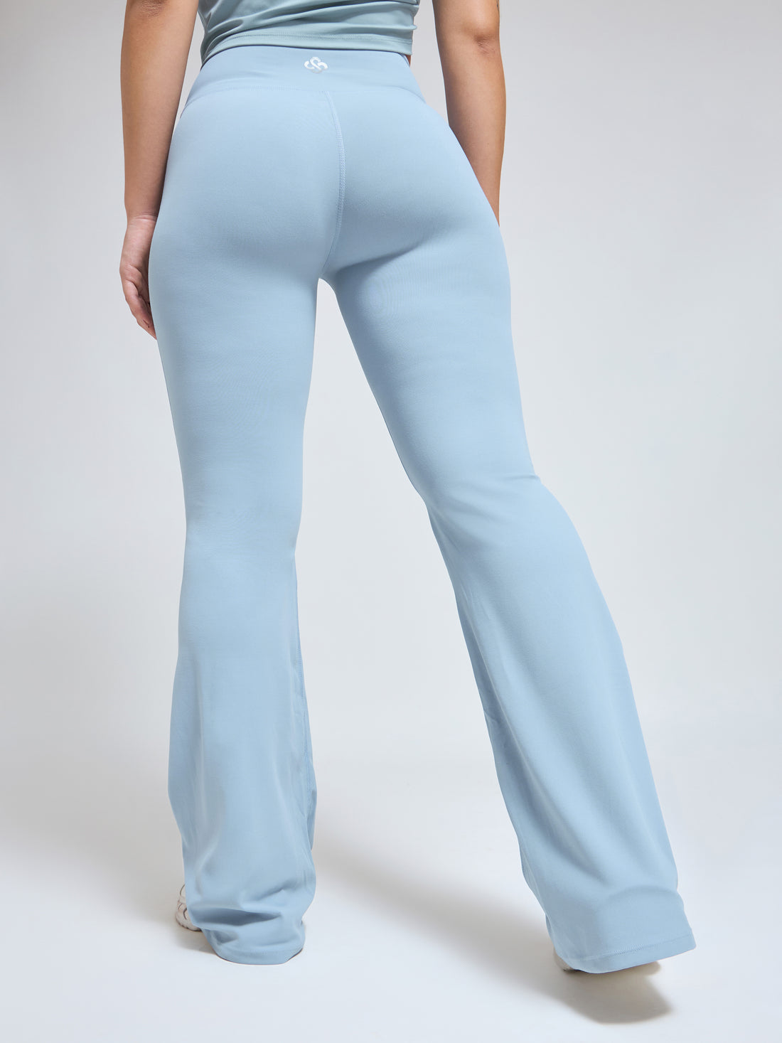 Woman wearing Infinito’s FlareFit High-Waisted Pants in sky blue, featuring a flared silhouette and supportive waistband for sculpted movement